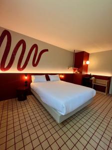 メリニャックにあるThe Originals City, Hôtel du Phare, Bordeaux Mérignacの壁にamのサインがあるホテルの部屋の大きなベッド