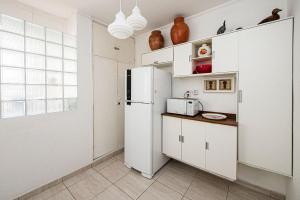 a kitchen with white cabinets and a refrigerator at Seu Refúgio em Santos, Pé na Areia in Santos