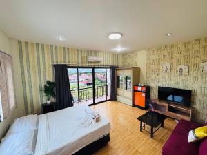 a hotel room with a bed and a television and a balcony at Jura 88 Guesthouse in Hua Hin