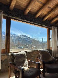 zwei Teddybären sitzen auf Stühlen und schauen aus dem Fenster in der Unterkunft Casa de Piedra in Potrerillos