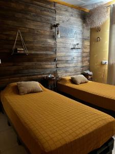 two beds in a room with wooden walls at Mírame Canarias in Vecindario