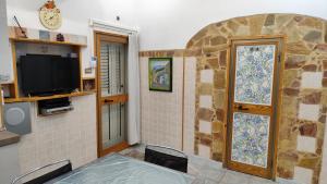 a room with a table and a tv and a stone wall at La Casetta Bianca Vicino Mare in Vibo Valentia Marina