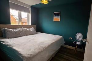 a bedroom with a bed with a blue wall at Newbury Garden Retreat in Headley