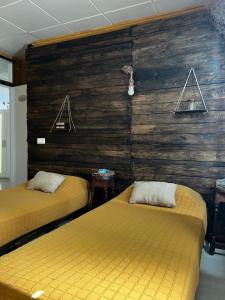 two beds in a room with a wooden wall at Mírame Canarias in Vecindario