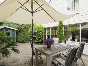 a wooden table with an umbrella on a patio at Holiday Home in Noordwijkerhout by Forest & Lake in Noordwijkerhout