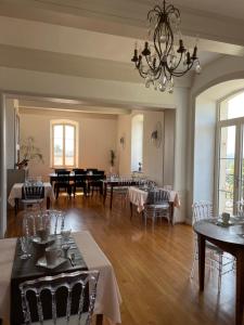 a dining room with tables and chairs and a chandelier at Château de Saint-Genix in Saint-Genix-sur-Guiers