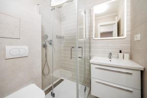 a white bathroom with a shower and a sink at APARTMENTS JADRANKa in Omišalj