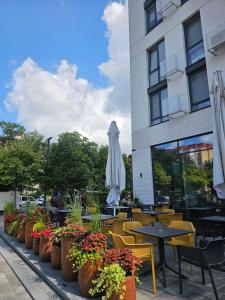 a cafe with tables and chairs and an umbrella at Nyvky Like Home - Файна Таун із сезонним басейном - Кв 6 низький поверх in Kyiv