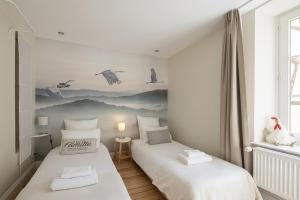 two twin beds in a room with white walls at Les Gites Du Retable in Colmar
