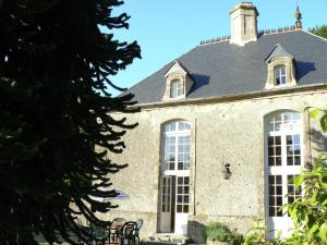 a large stone building with white windows and a roof at 18th-Century Normandy Stay in Valognes