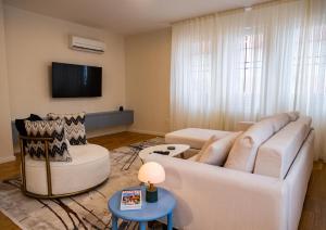 un salon avec un canapé blanc et une télévision dans l'établissement Kaizen's Central Apartments - Free Parking, à Sarajevo