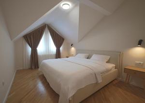 une chambre avec un grand lit blanc et une fenêtre dans l'établissement Kaizen's Central Apartments - Free Parking, à Sarajevo