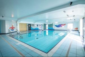 a large swimming pool with two chairs in a building at Jen's Retreat in Lossiemouth