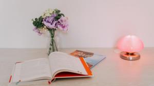 an open book on a table with a vase of flowers at L'Appart Sud Vendée in Saint-Hilaire-des-Loges