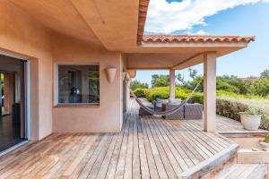 una terraza de madera con una hamaca en una casa en Villa Pina, en Sainte-Lucie de Porto-Vecchio