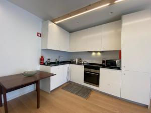 a kitchen with white cabinets and a wooden table at Ó Maria in Alcácer do Sal