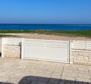 a white gate with the beach in the background at Trulli sul Mare Forcatella in Savelletri di Fasano