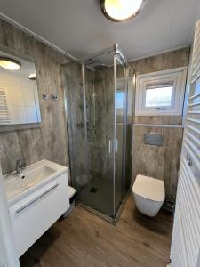 a bathroom with a shower and a toilet and a sink at Recreatie Chalet in Dordrecht
