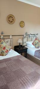 a hotel room with two beds and a table with a lamp at Leuchars Guest House in Greytown