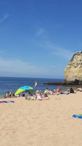 um grupo de pessoas em uma praia com guarda-sóis em Apartamento Madalena em Carvoeiro