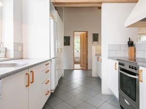 a kitchen with white cabinets and a tile floor at 4 star holiday home in Hjørring in Lønstrup