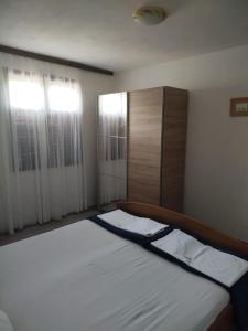 a bedroom with a bed and a cabinet and windows at Apartmani Katarina in Rogoznica +3 photos