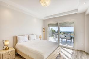 a white bedroom with a bed and a balcony at Prime Holidays Mountain View Ras ElHekma in Ras Elhekma