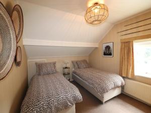 a bedroom with two beds and a chandelier at Villa in Ommen with Private Pond in Rheezerveen