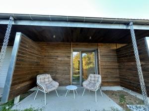 two chairs and a table on the porch of a house at Logis Hébergement et Restaurant La Vallée in Peyraud