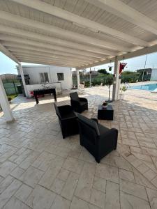 acovered patio with chairs and a table and a pool at Villa acqua e sale in Santa Maria Del Focallo +2 photos