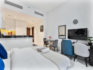una camera da letto con due letti, un tavolo e delle sedie di Savis Homes - Furnished Spacious Studio in Golf Promenade 2A by Damac Hills a Dubai