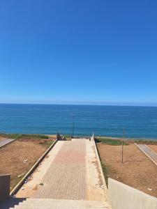 un chemin de briques menant à l'océan par temps clair dans l'établissement Sea View Apartment, à Sidi Bouqnadel