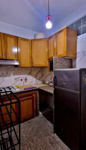 Una cocina con gabinetes de madera y un refrigerador negro. en Greeny Studio, en Rabat