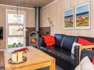 ein Wohnzimmer mit einem Ledersofa und einem Kamin in der Unterkunft 6 person holiday home in Hemmet-By Traum in Falen
