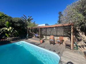 een zwembad op een houten terras met een tuinhuisje bij The Berg Surf Shack in Muizenberg