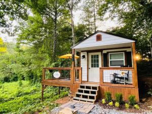 a tiny house with a porch and an umbrella at Jai Hollow Tiny Home Cottage in Robbinsville
