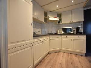 a kitchen with white cabinets and a microwave at Chalet in Veluwe near Sauna Drôme in Putten