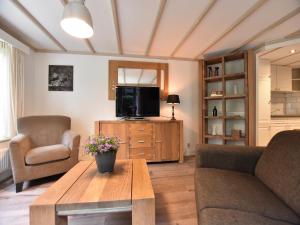 a living room with a couch and a tv and a table at Chalet in Veluwe near Sauna Drôme in Putten
