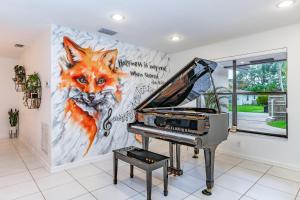 Un piano en una habitación con una pintura de un zorro. en Fox Island Heated Spa- Downtown & Beach, en Fort Lauderdale