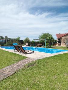 a swimming pool with two chairs in a yard at Cabaña 4B Azahares del Ayui in Concordia