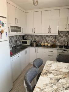 a kitchen with white cabinets and a table with chairs at Star Apartment Derya Izmir in Konak