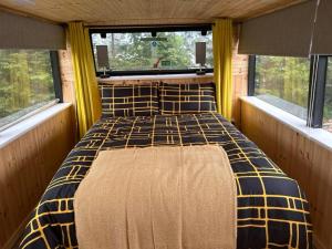 a bed in the middle of a room with two windows at Bus Vacation in Corran Cross Roads