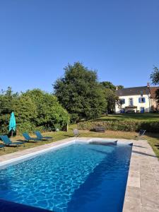 a swimming pool with chairs and a house in the background at Les Marronniers Gîtes in Crozant