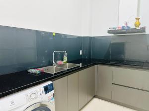 a kitchen with a sink and a washing machine at Vincom Shophouse in Dong Hoi