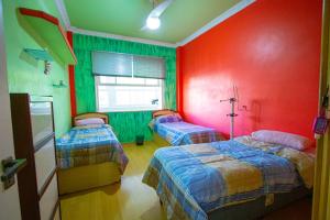 two beds in a room with red and green walls at APT Perto da praia de Copacabana in Rio de Janeiro