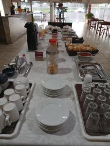 a long table with white plates and dishes on it at Hotel Castro Alves Norte in Marília