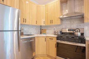 a kitchen with wooden cabinets and a stainless steel refrigerator at Bright & Cozy 3Bd Brooklyn Getaway in Brooklyn +17 photos