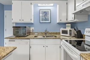 eine Küche mit weißen Schränken und einer Spüle in der Unterkunft Plantation 1211 in Gulf Highlands + 27 Fotos