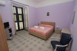 a bedroom with a bed and a chair at Villa Azzurra Apartment Camilleri's Roads in Porto Empedocle