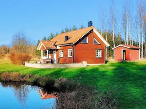 a house on a hill with a pond in front of it at 6 person holiday home in Vittsjö in Vittsjö